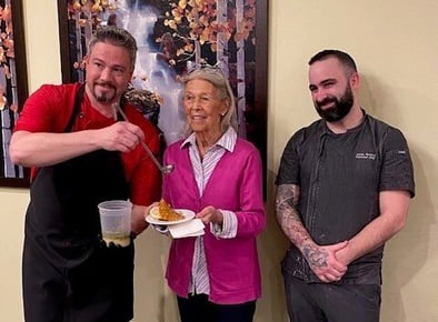 Red Oak, Executive Chef James Rennick and Sous Chef Travis pose with resident Bonnie, holding a sample of her recipe, Chicken French