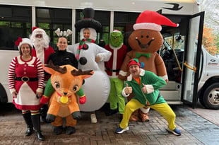 Astoria team members dressed up in holiday costumes in front of their bus