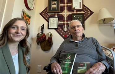 Bob Wells, a resident at Granite Ridge sits beside Kyarah Donnelly Director of Resident Programs, holding two books he authored