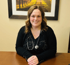 Mandi, a nurse at Aspira West Park Crossing, sits at a desk and is smiling