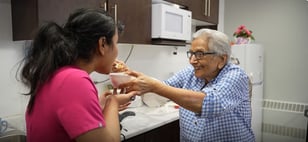 Jagjit feeds a team member a bite of her new recipe