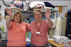 Terry and a Sienna team member wave while volunteering in the laundry department