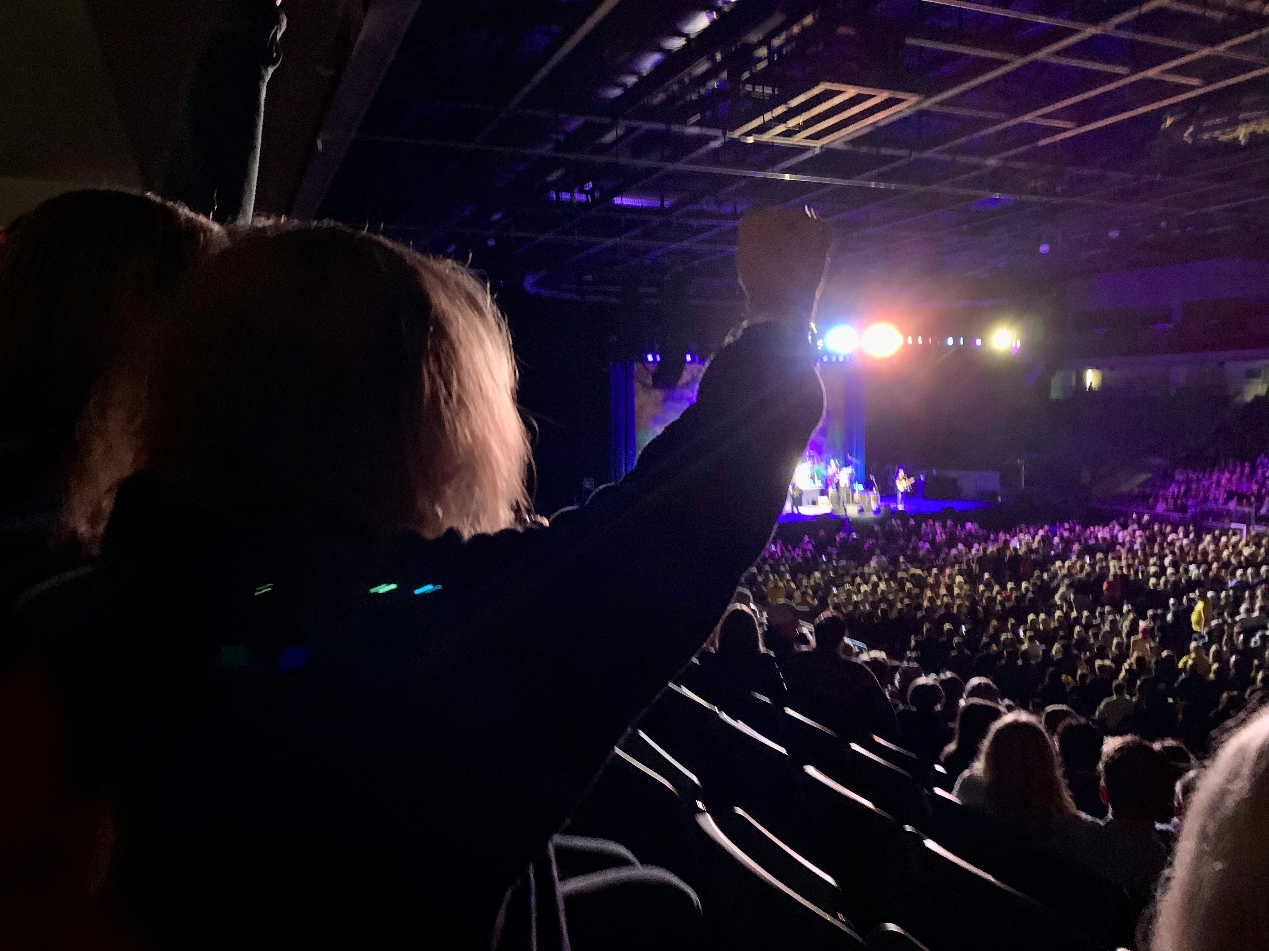 Debbie at the concert raising her hands 
