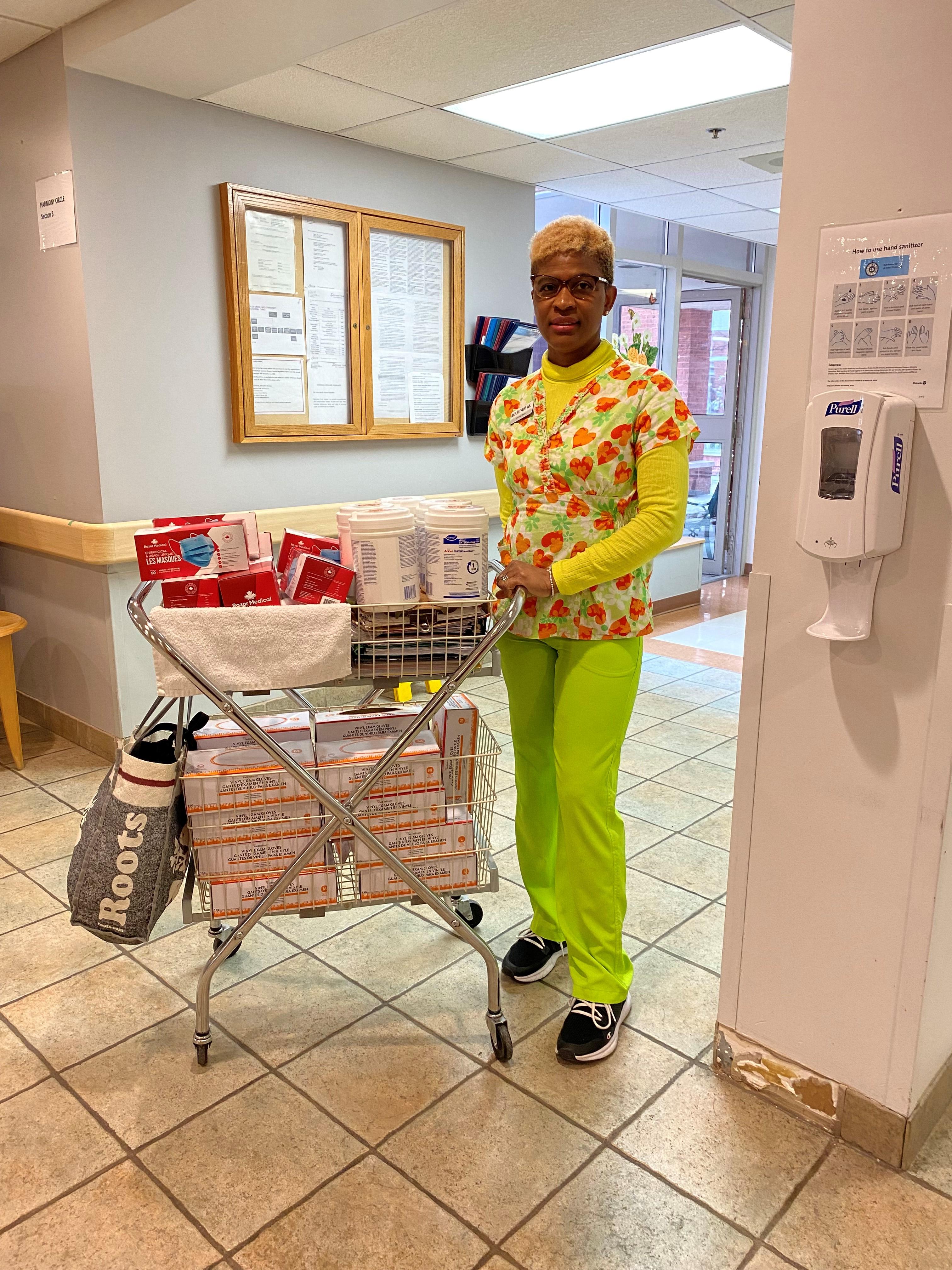 Marian, a psw and IPAC Champ, stands with her supply cart